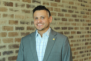 Man posing for photo in front of a brick wall
