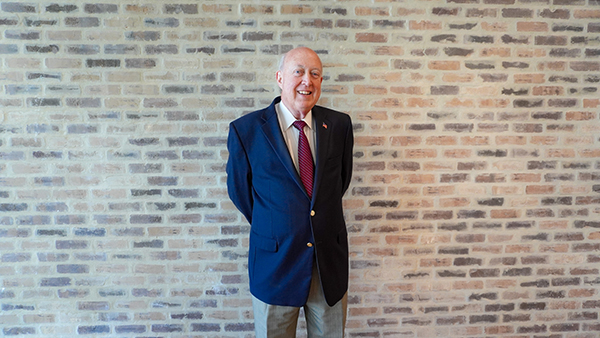 Man standing in front of a brick wall smiling