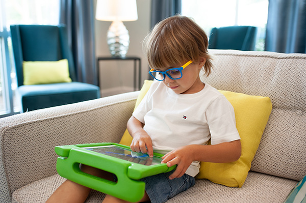 Child sitting on couch using ipad