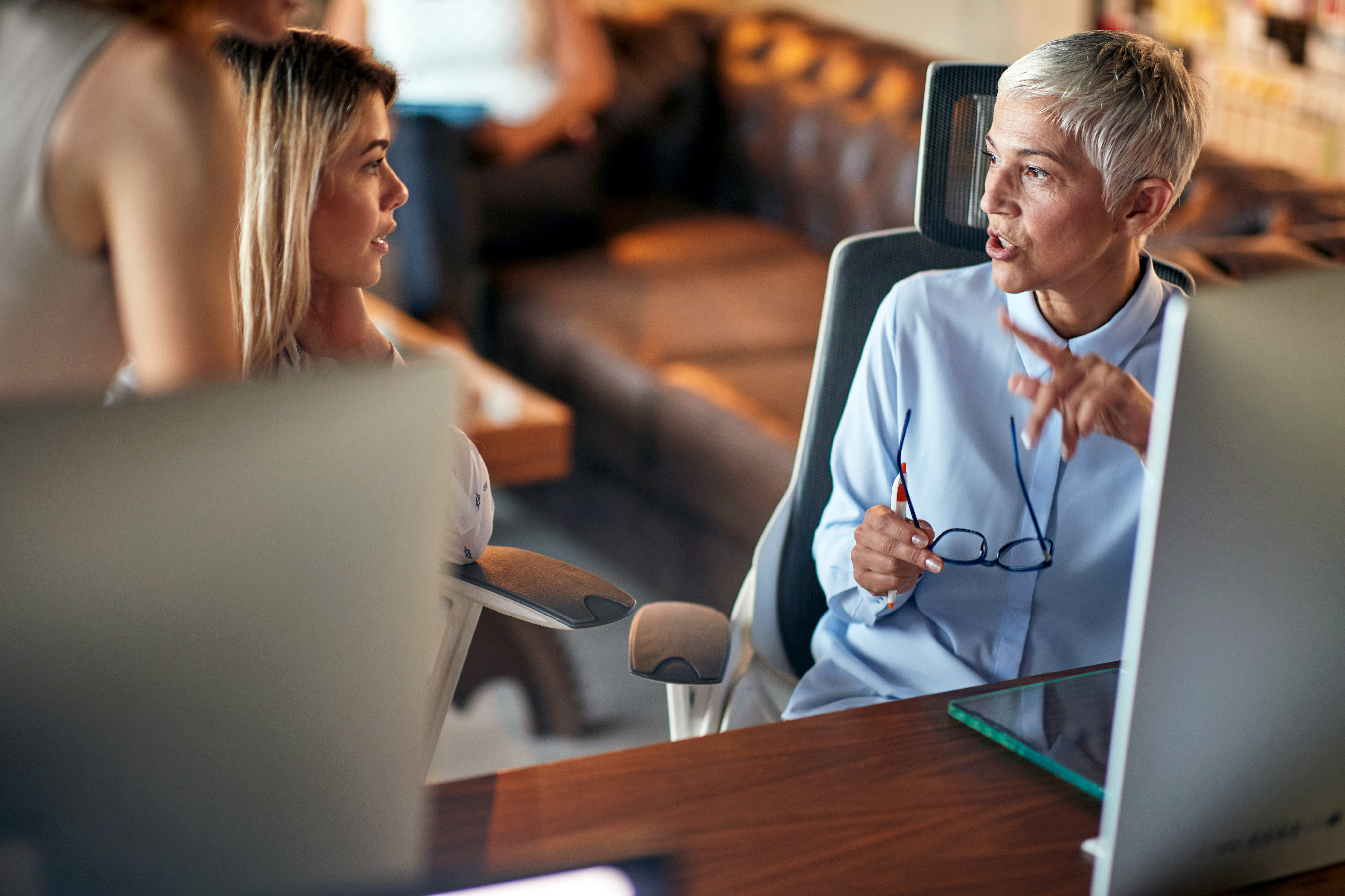 Two professional women talking in an office, representing mentorship and confident financial decision-making