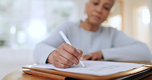 Woman writing on a piece of paper with a serious expression