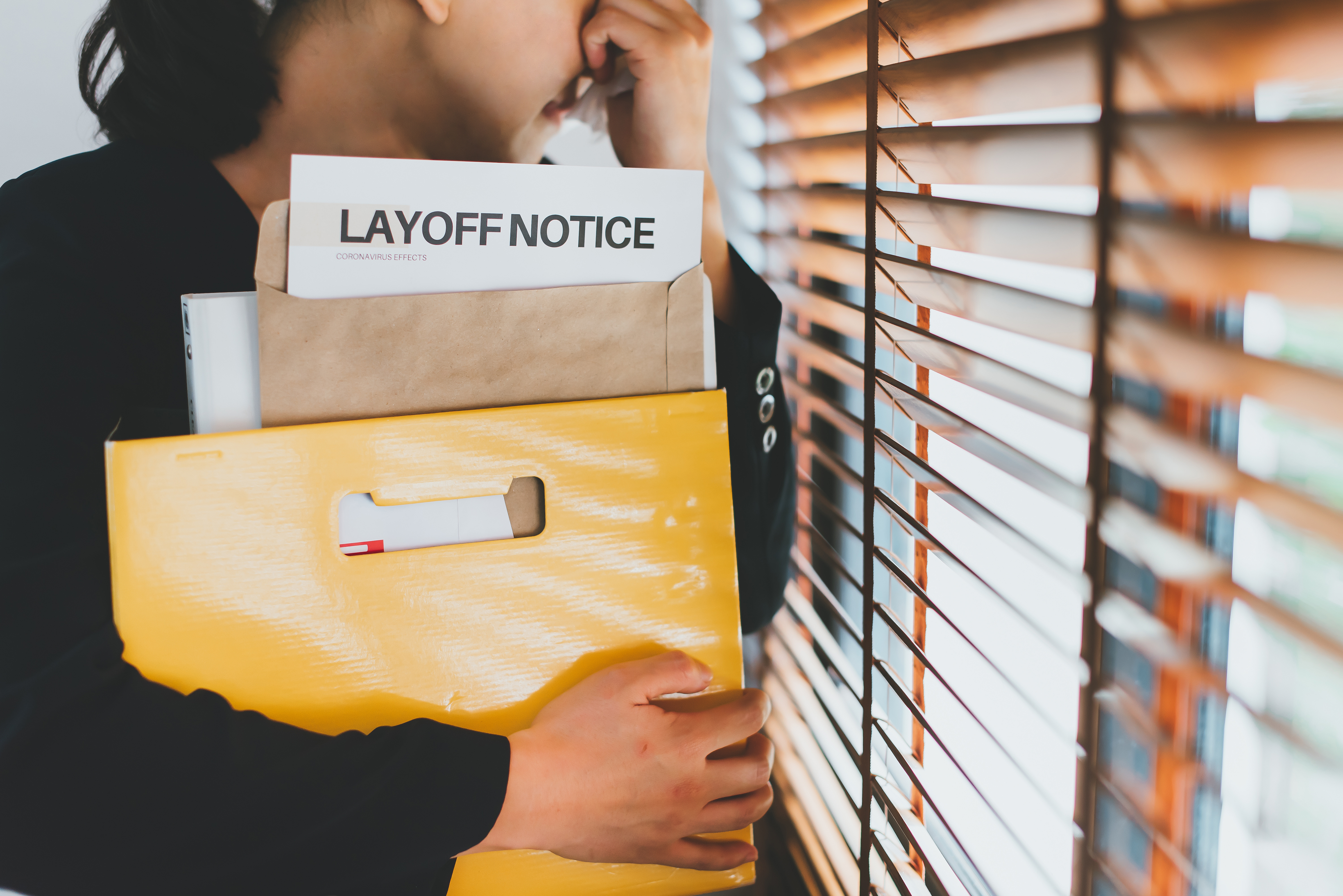 Person holding a layoff notice, representing income loss and the need for an emergency savings fund