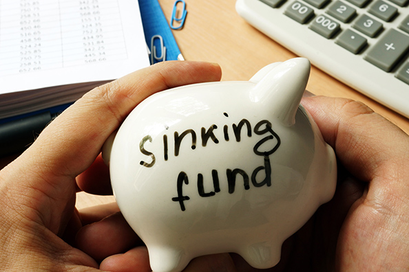 White piggy bank labeled sinking fund symbolizing planned savings for future expenses