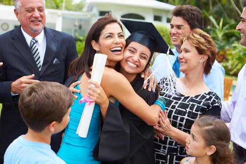 Student hugging her parents at graduation.