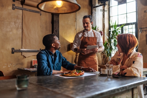 Couple speaking with their waiter at a nice restaurant. 