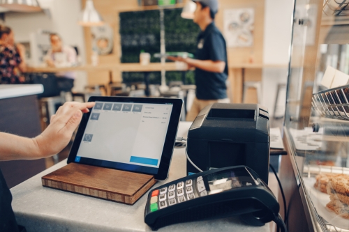 A person using a point of sale system in a bakery.