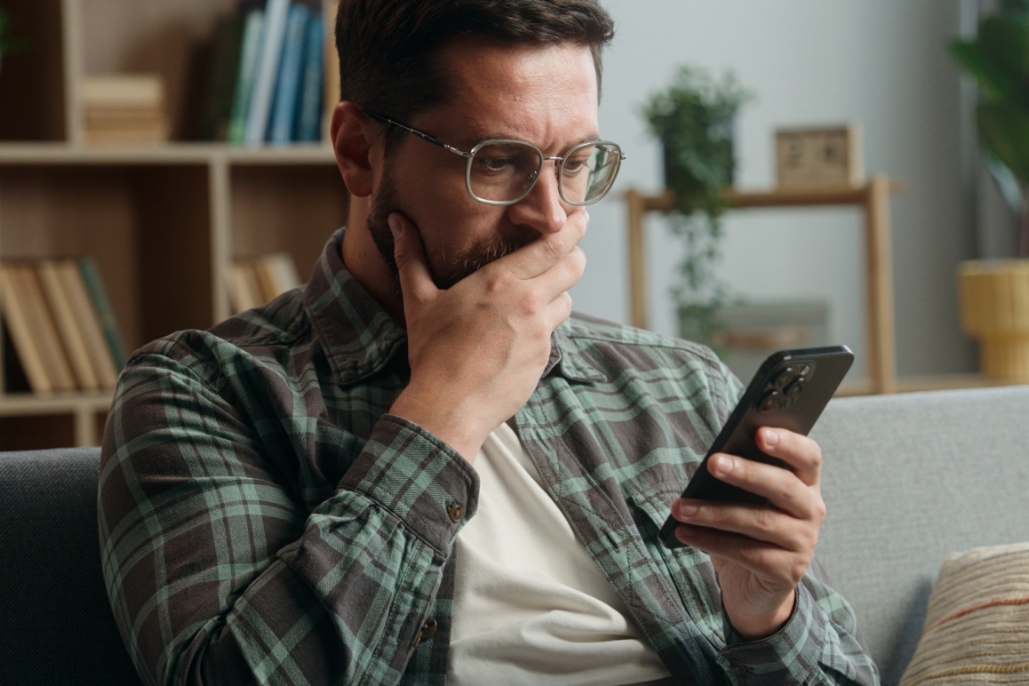 Man looking concerned while reading a possible scam message on his phone