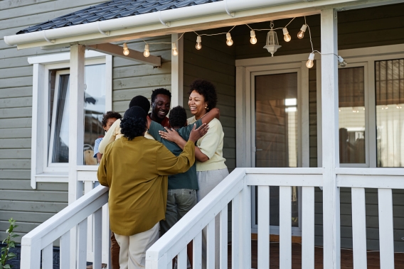 A family hugging on their front porch celebrating the purchase of their new home. 