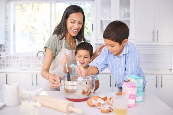 A mother and her children baking in their home's kitchen. 