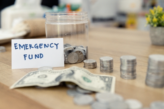 Jar labeled emergency fund filled with coins and cash, symbolizing building financial resilience through savings