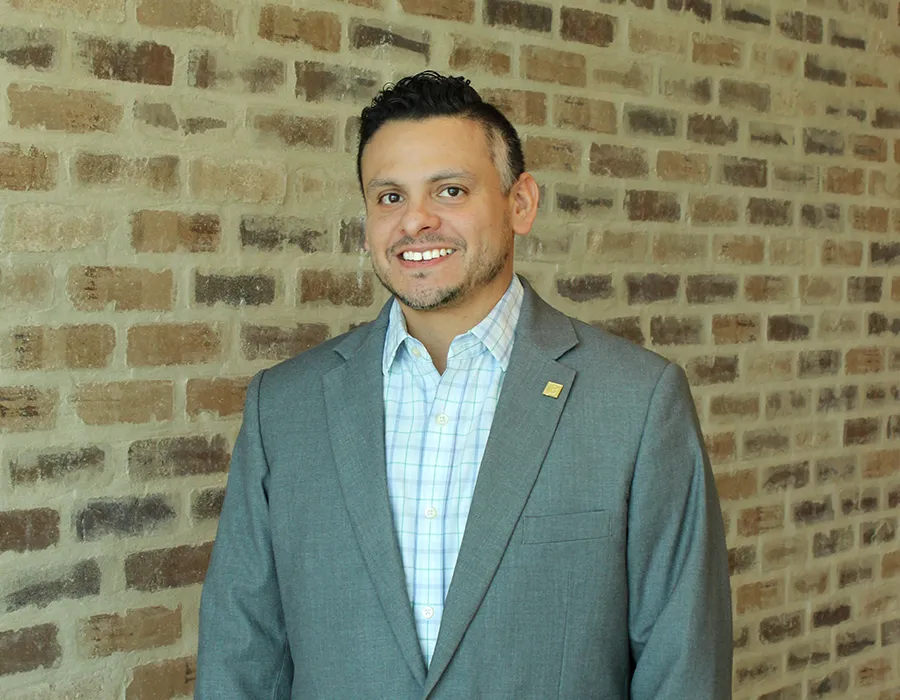 Man posing for photo in front of a brick wall. 